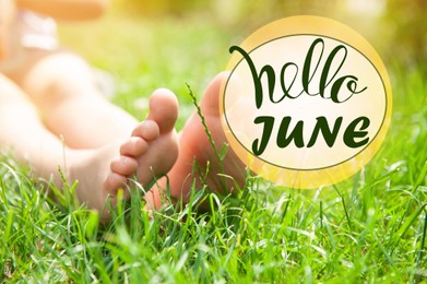 Image of Hello June. Child sitting barefoot in green grass on sunny day, closeup