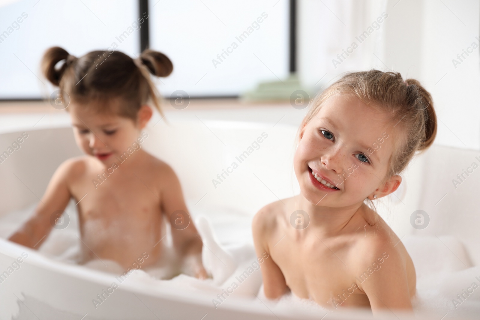 Photo of Cute little sisters taking bubble bath together