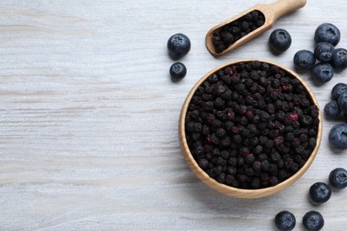 Photo of Freeze dried and fresh blueberries on white wooden table, flat lay. Space for text