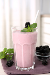 Photo of Tasty blackberry milk shake with fresh berries on table