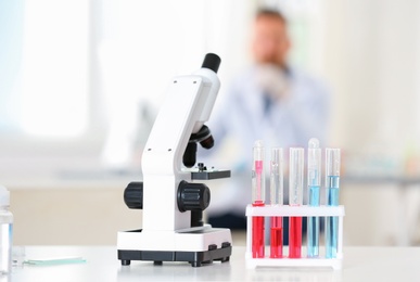 Rack with test tubes and microscope on table in laboratory. Research and analysis