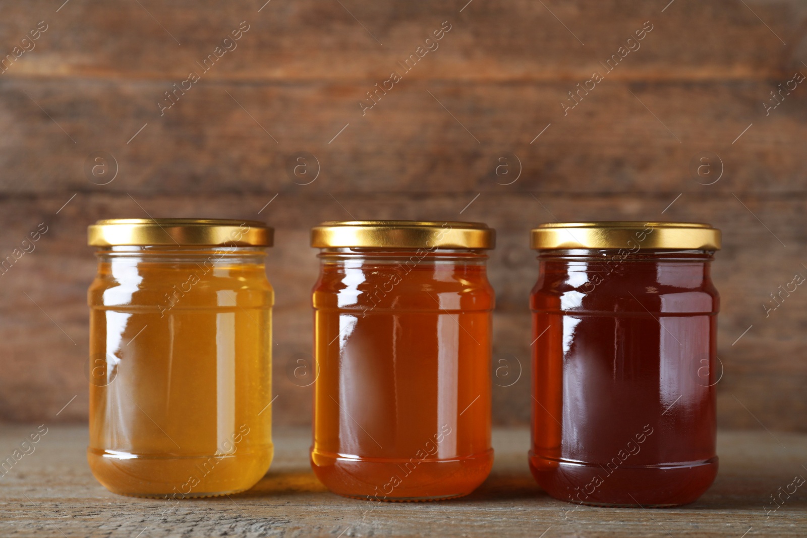 Photo of Jars with different types of organic honey on wooden table