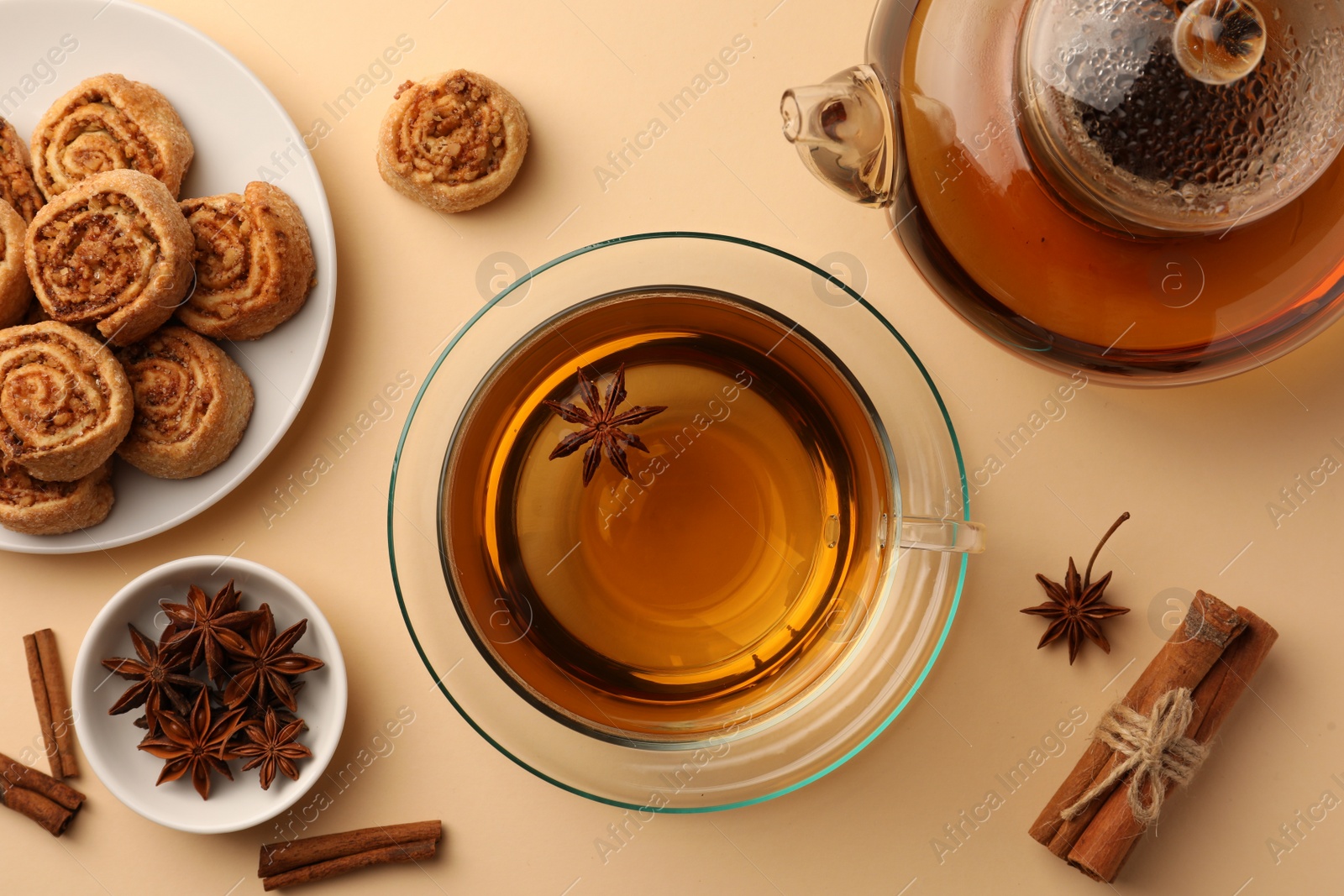 Photo of Flat lay composition with aromatic tea, cookies and anise stars on beige table