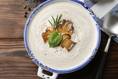 Photo of Delicious homemade mushroom soup served on wooden table, flat lay