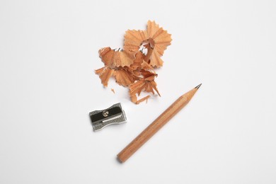 Sharp graphite pencil, shavings and sharpener on white background, flat lay