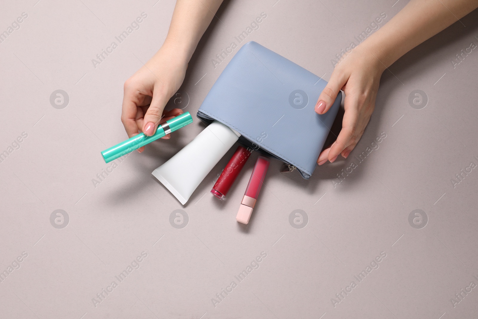 Photo of Woman with cosmetic bag and different makeup products on beige background, top view