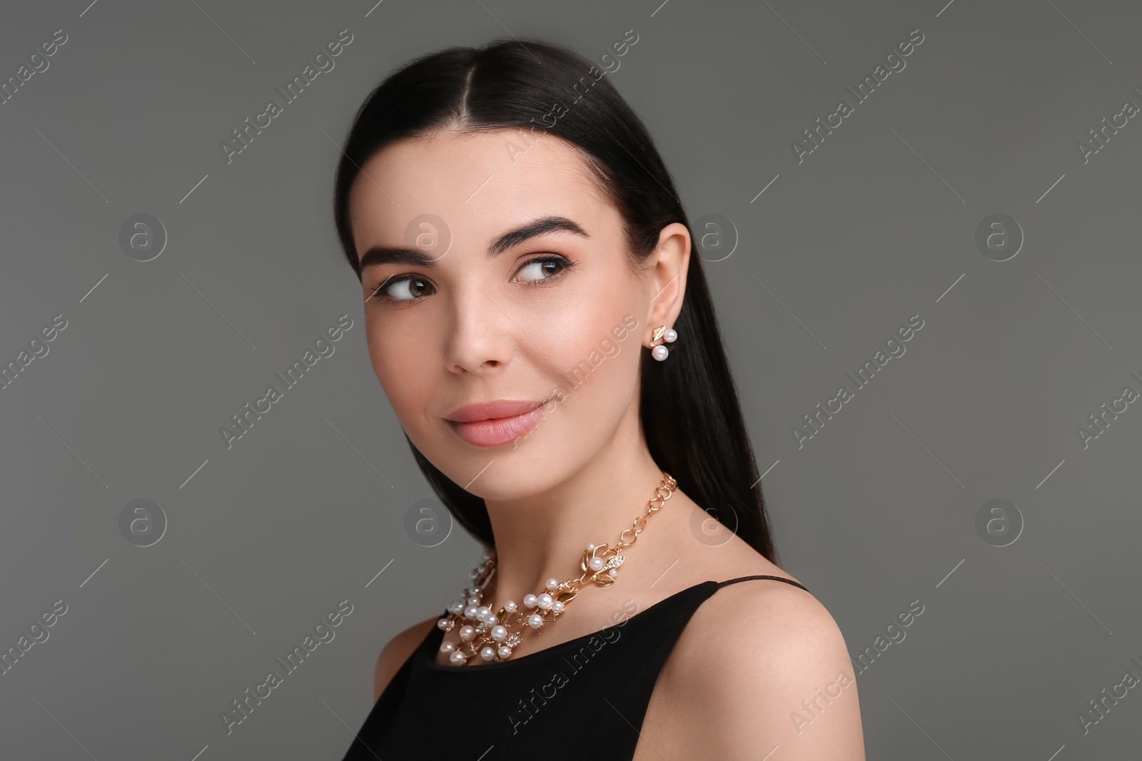 Photo of Beautiful young woman with elegant jewelry on dark grey background