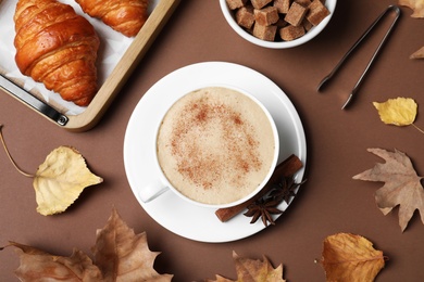Photo of Flat lay composition with cup of hot drink on brown background. Cozy autumn atmosphere