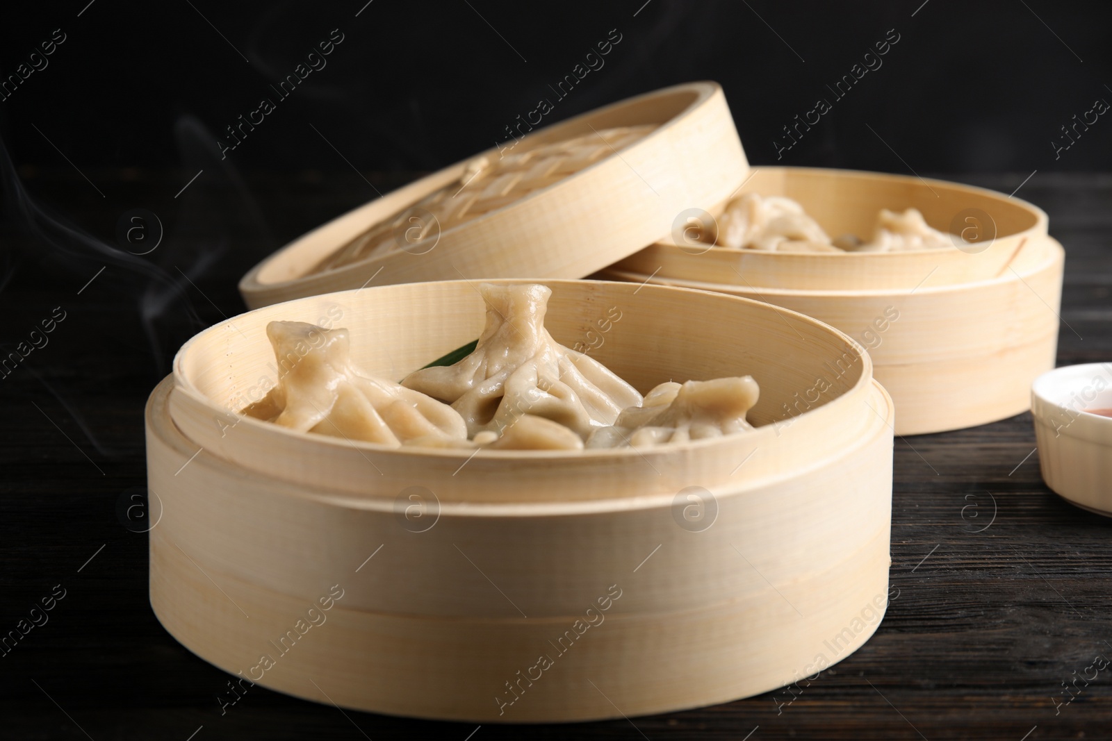 Photo of Bamboo steamer with tasty baozi dumplings on table