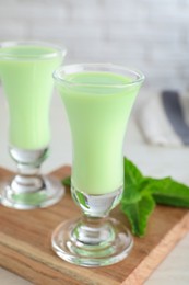 Delicious mint liqueur on wooden board, closeup