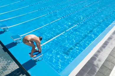 Image of Man training in outdoor swimming pool on sunny day 