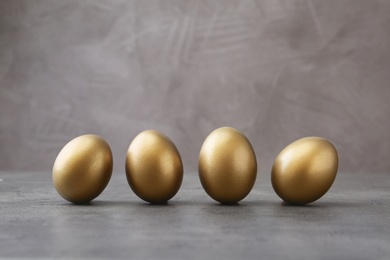 Many shiny golden eggs on grey table
