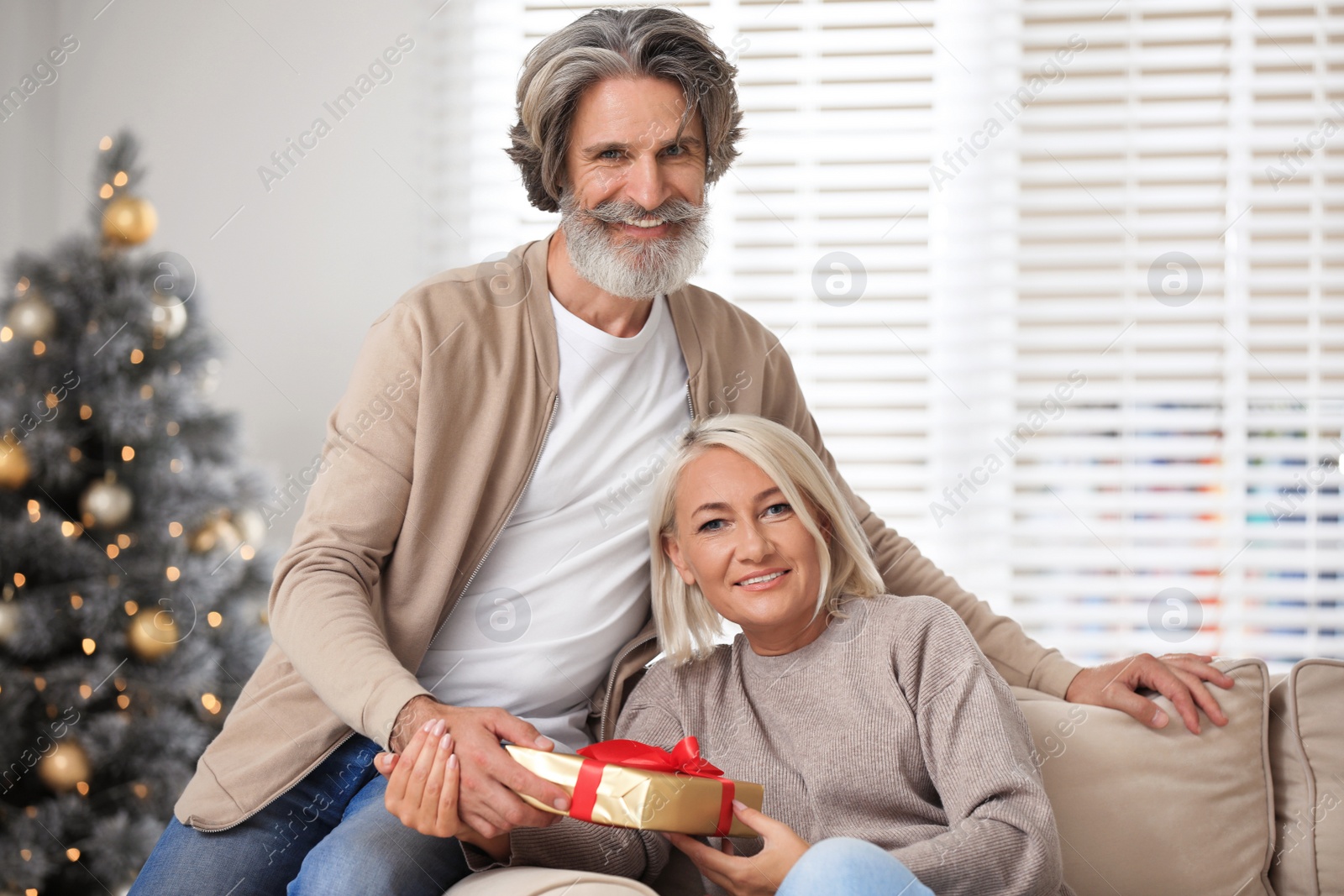 Photo of Happy couple opening Christmas gift at home