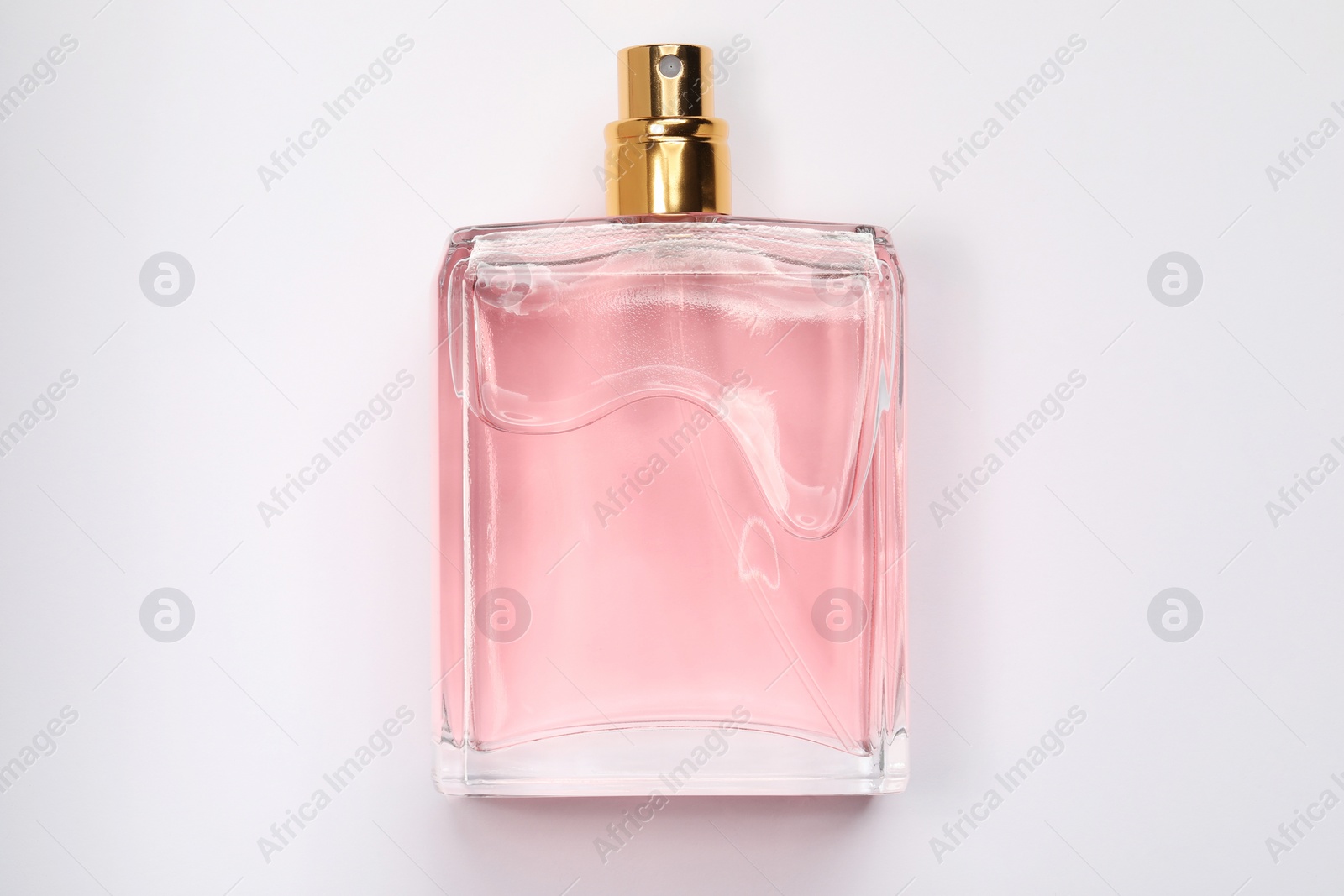 Photo of Pink women's perfume in bottle on white background, top view