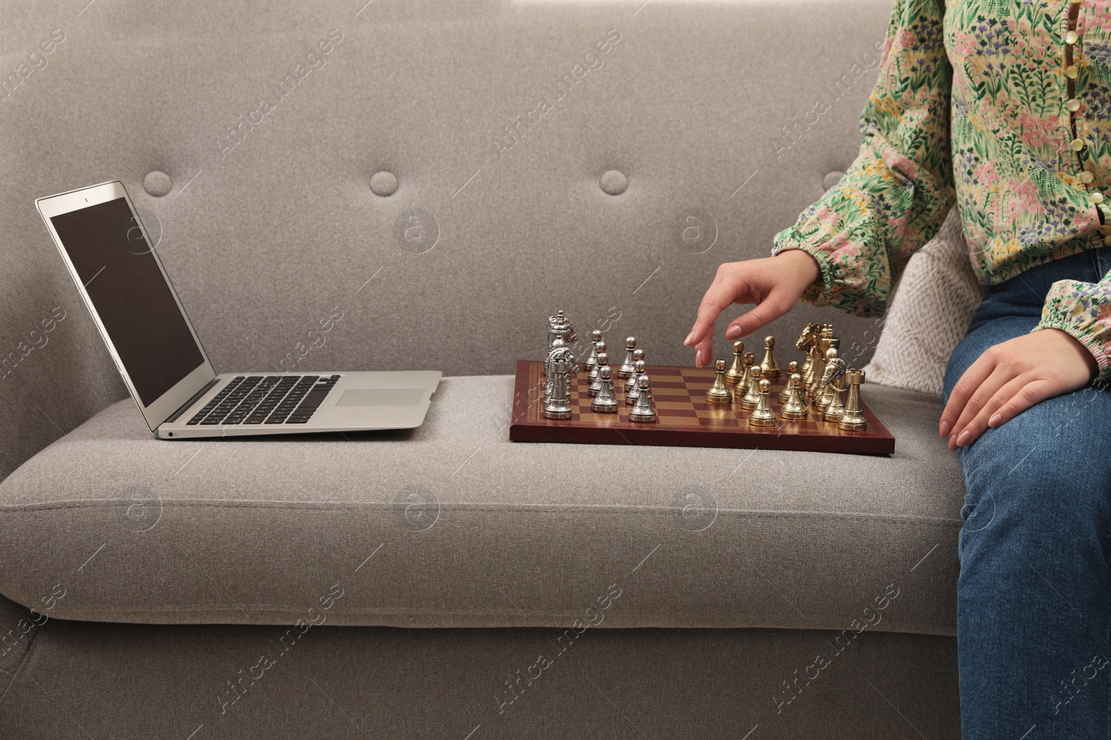 Photo of Woman playing chess with partner through online video chat on sofa, closeup