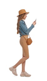 Photo of Young woman in casual outfit using smartphone while walking on white background