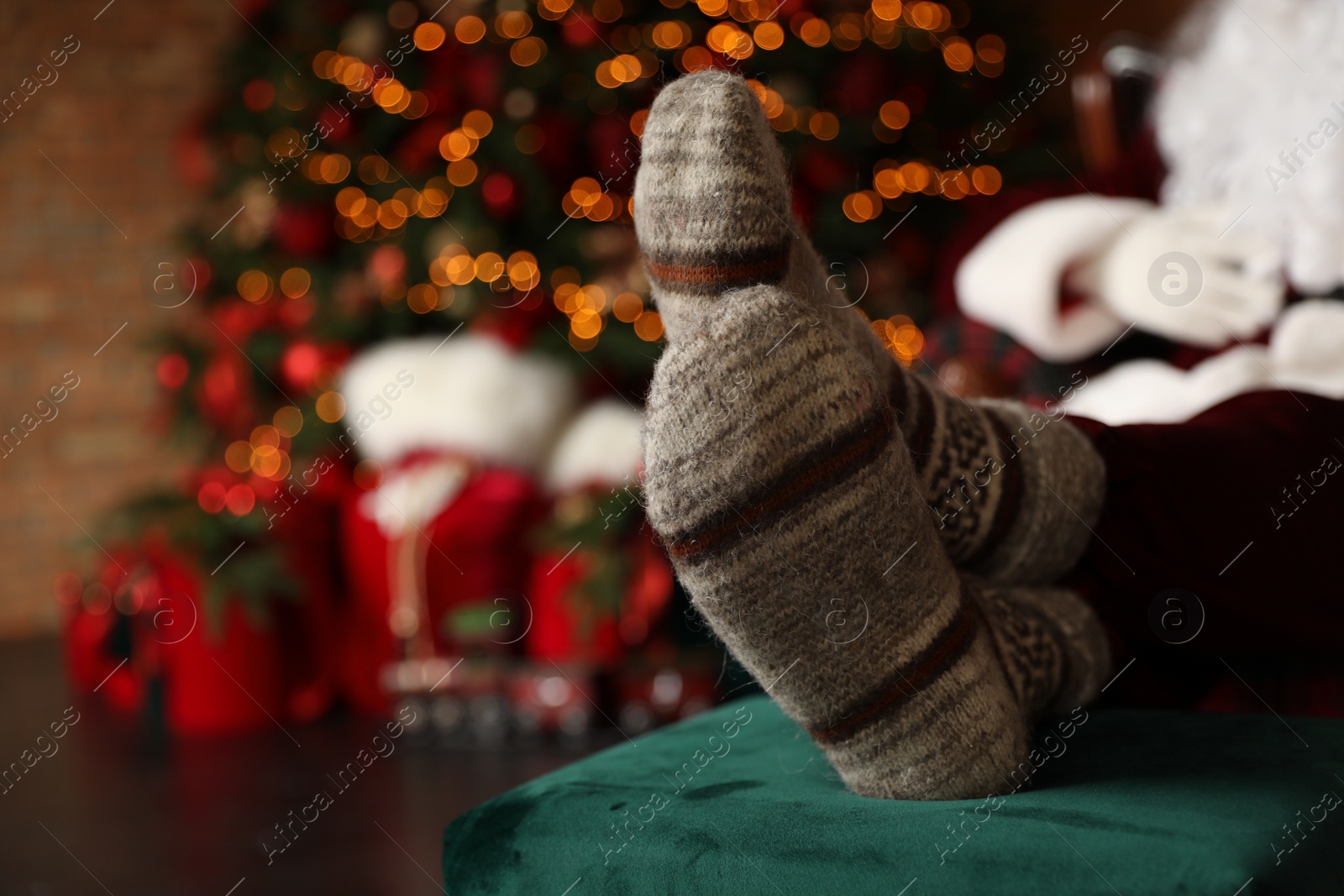 Photo of Santa Claus wearing woolen socks against blurred Christmas lights, closeup