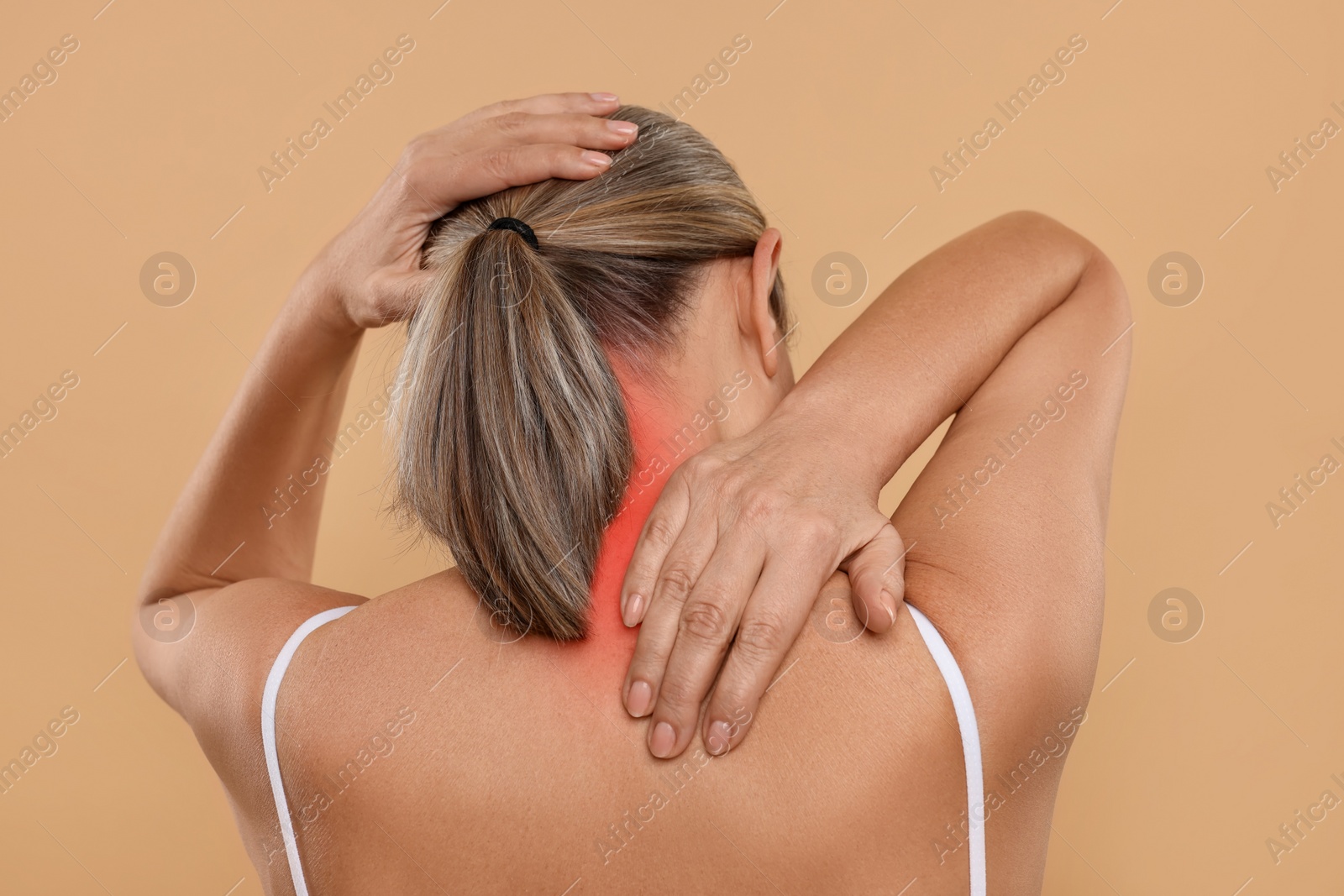 Image of Woman suffering from neck pain on dark beige background, back view