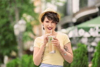 Young woman with cup of tasty lemonade outdoors