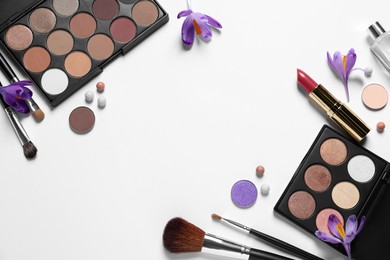 Photo of Flat lay composition with eyeshadow palettes and beautiful crocuses on white background, space for text