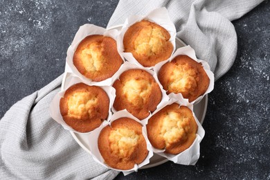 Delicious sweet muffins on black textured table, top view