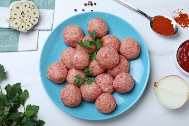 Many fresh raw meatballs and ingredients on white table, flat lay