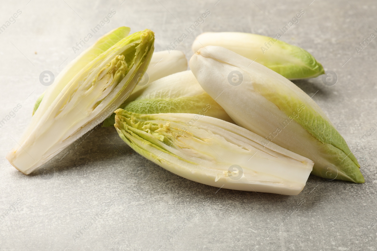 Photo of Fresh raw Belgian endives (chicory) on light grey table