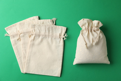Photo of Cotton eco bags on green background, flat lay
