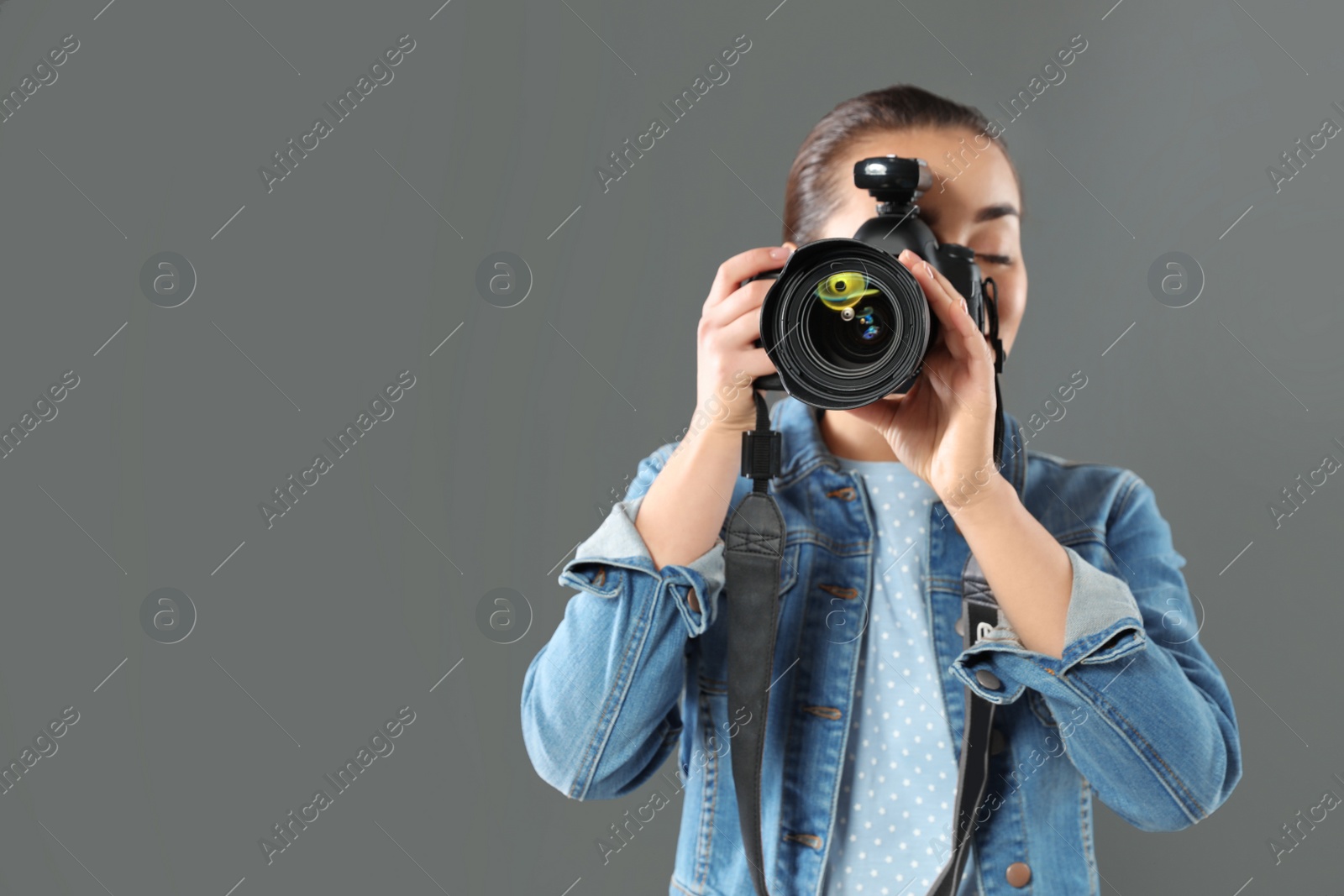Photo of Young woman with camera and space for text on gray background. Professional photo studio