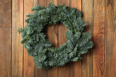 Photo of Christmas wreath made of fir tree branches on wooden background