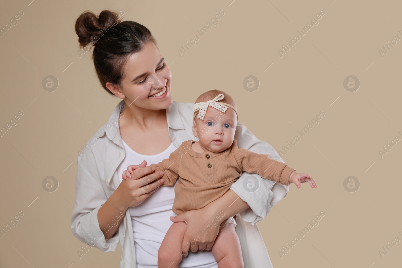 Photo of Beautiful mother with her cute baby on beige background