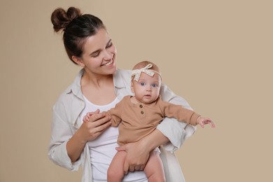 Beautiful mother with her cute baby on beige background