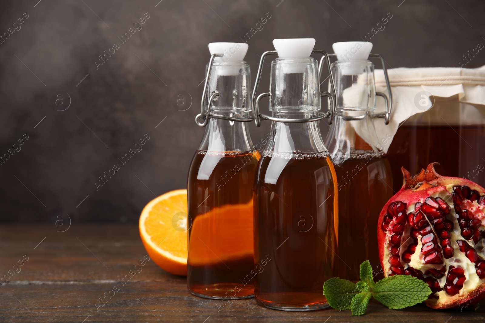 Photo of Tasty kombucha, mint and fresh fruits on wooden table, space for text