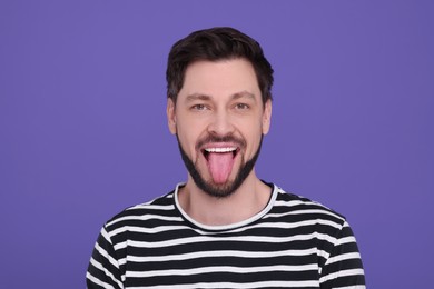 Photo of Happy man showing his tongue on purple background