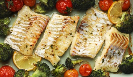 Photo of Pieces of delicious baked cod with vegetables and spices in dish, top view