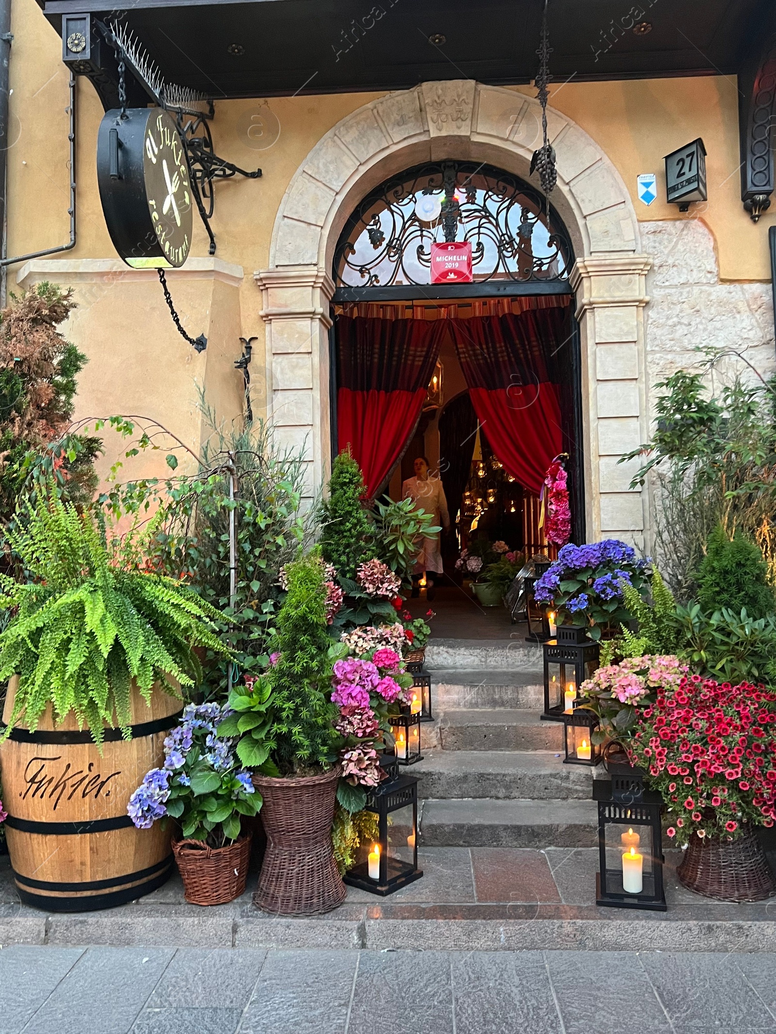 Photo of WARSAW, POLAND - JULY 15, 2022: Beautiful plants and lanterns near entrance in restaurant