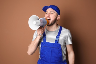 Photo of Male worker shouting into megaphone on color background