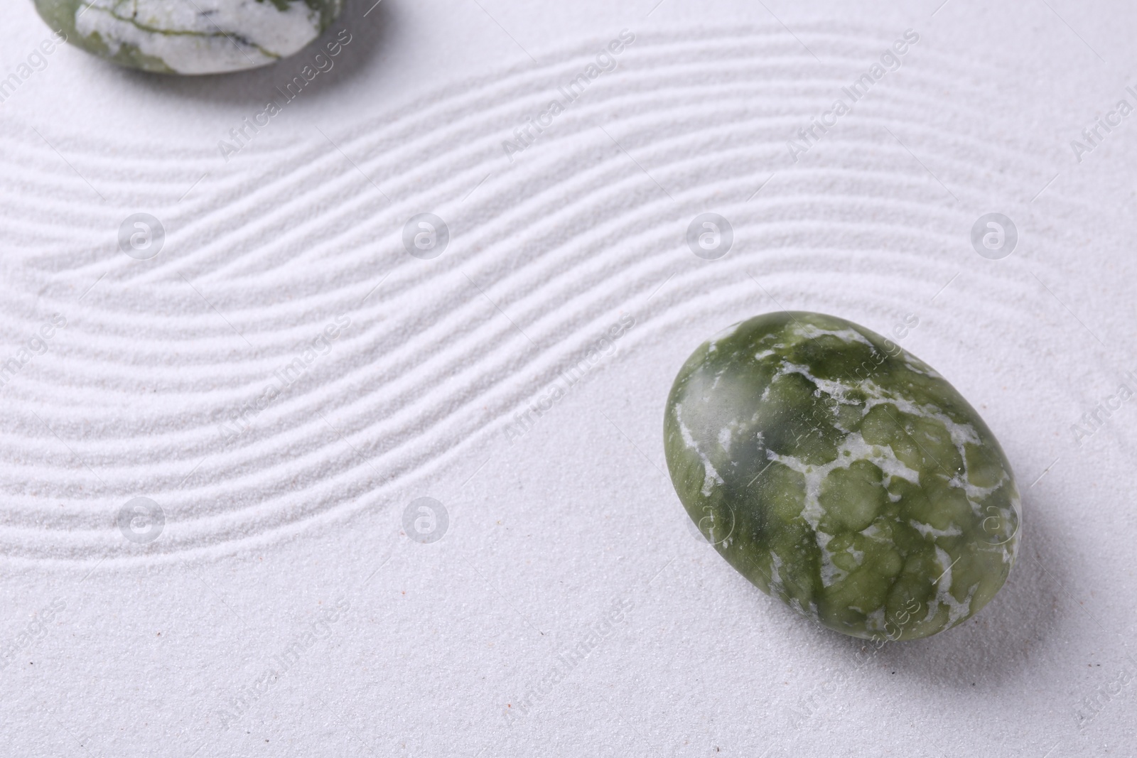 Photo of Stones on sand with pattern, above view. Zen concept