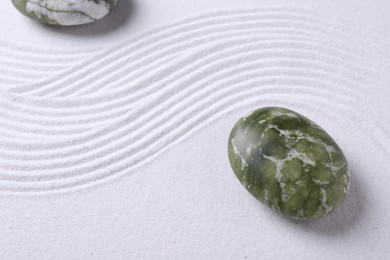 Photo of Stones on sand with pattern, above view. Zen concept