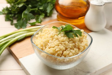 Photo of Delicious bulgur with parsley in bowl and products on table, closeup