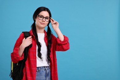 Photo of Student in glasses with backpack on light blue background. Space for text