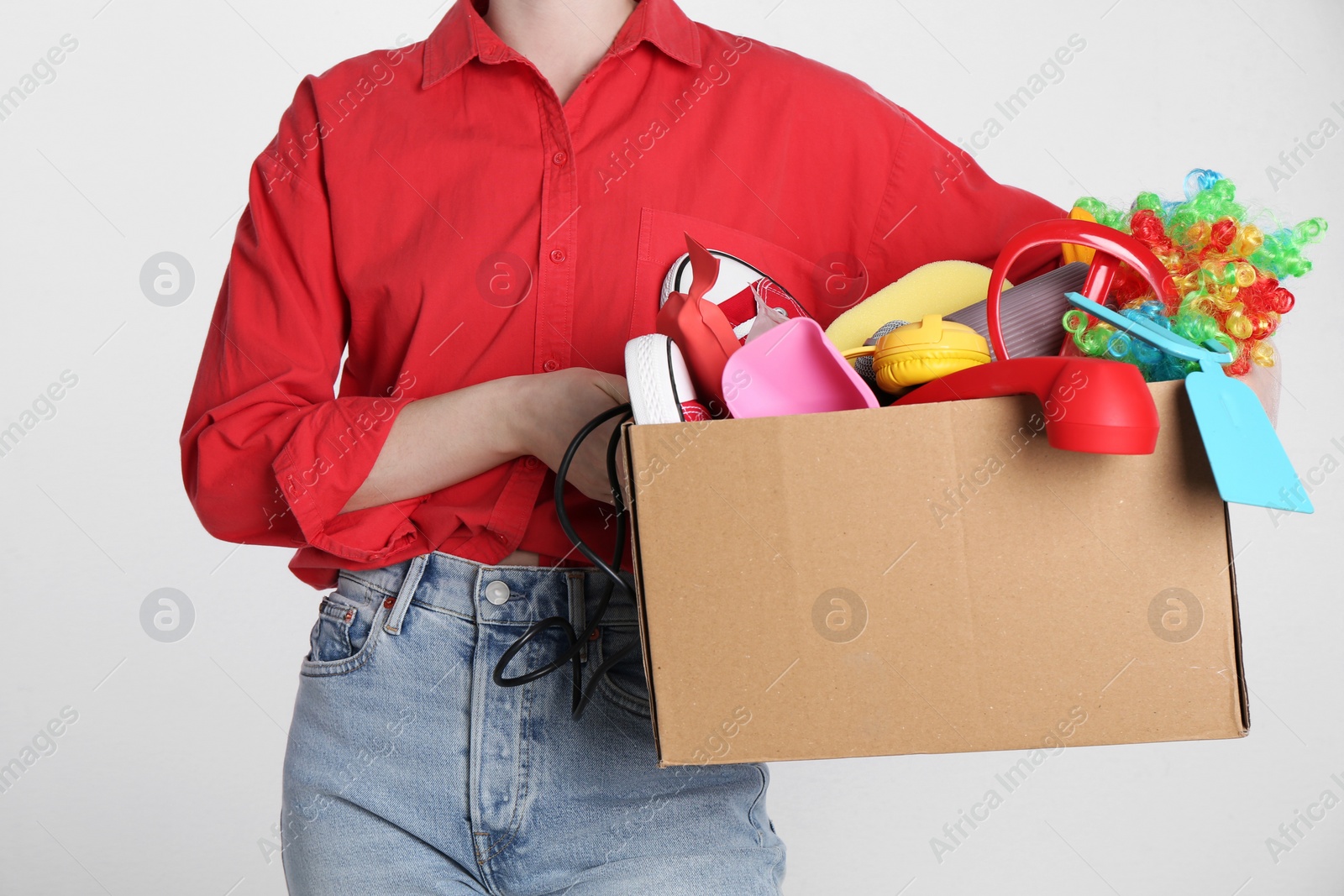 Photo of Woman holding box of unwanted stuff on white background, closeup