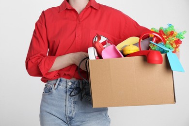 Woman holding box of unwanted stuff on white background, closeup