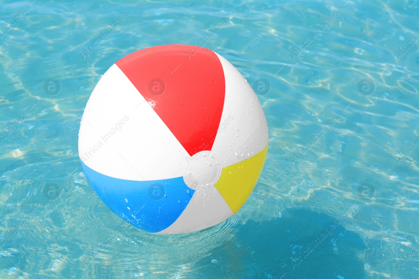 Photo of Colorful beach ball floating in sea on sunny day, space for text