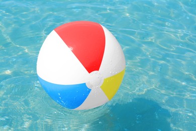 Colorful beach ball floating in sea on sunny day, space for text