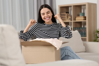 Emotional young woman with parcel at home. Internet shopping