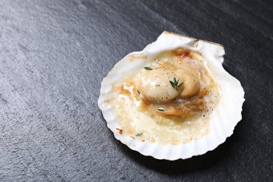 Photo of Fried scallop in shell on black table, closeup. Space for text