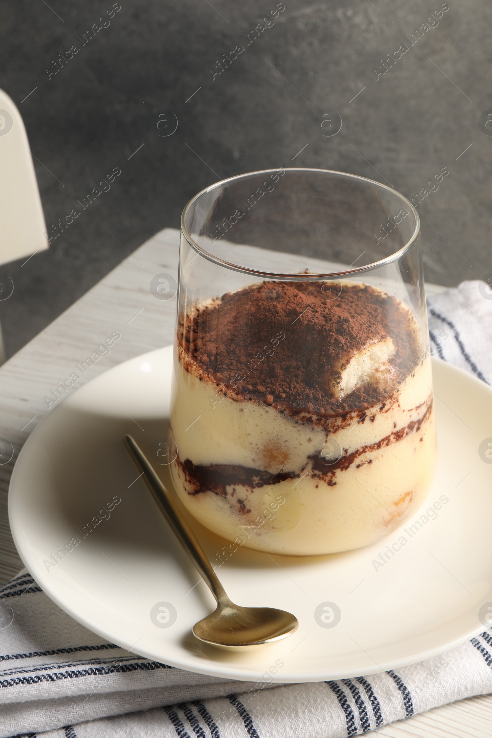 Photo of Delicious tiramisu in glass on white wooden table