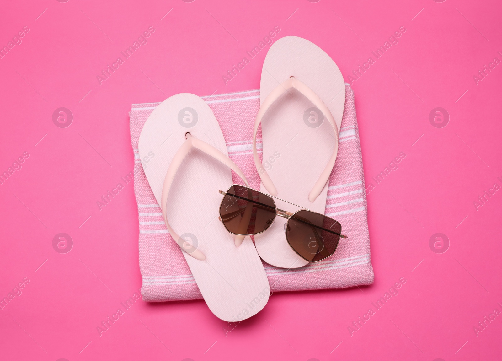 Photo of Towel, flip flops and sunglasses on pink background, top view. Beach objects