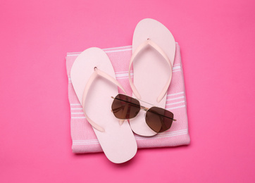 Photo of Towel, flip flops and sunglasses on pink background, top view. Beach objects